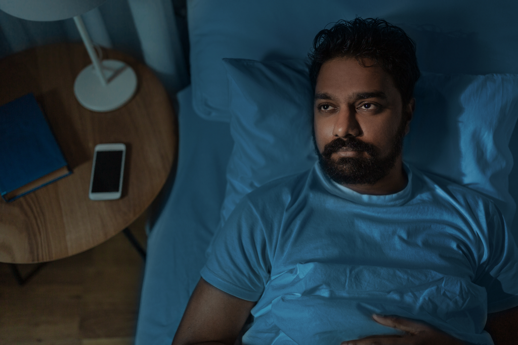 अनिद्रा (Insomnia) और अधूरी नींद से पाएं स्थायी छुटकारा: जानिए गहरी नींद के 8 असरदार घरेलू नुस्खे sleepless indian man lying in bed at home at night