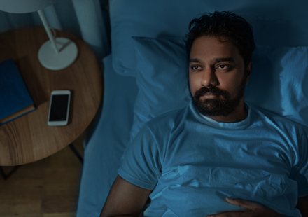 sleepless indian man lying in bed at home at night